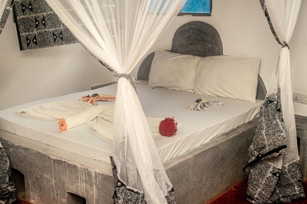 a swing bed with white curtains and dolls on it at Stonefish Inn Jambiani in Jambiani