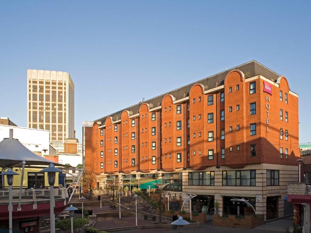 a large red brick building in a city at ibis Birmingham Centre New Street Station Hotel in Birmingham