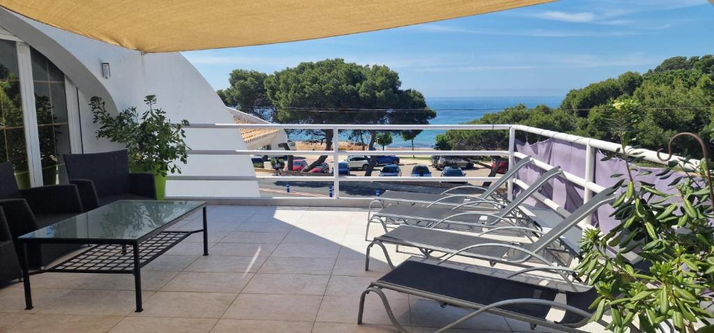 a balcony with a table and chairs and the ocean at Beachfront Villa in Moraira