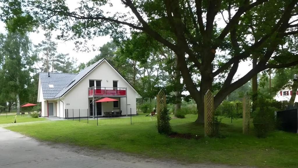 a white house with a tree in the yard at Haus Eichenkrone in Bodstedt