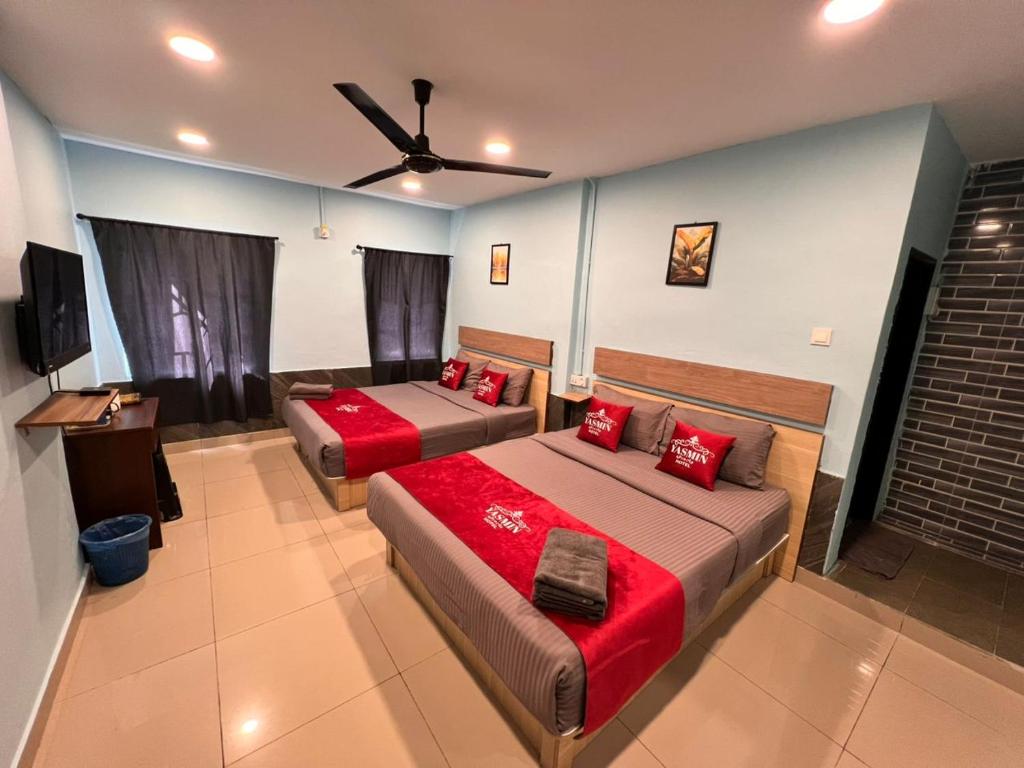 a bedroom with two beds with red pillows at Hotel Yasmin in Brinchang