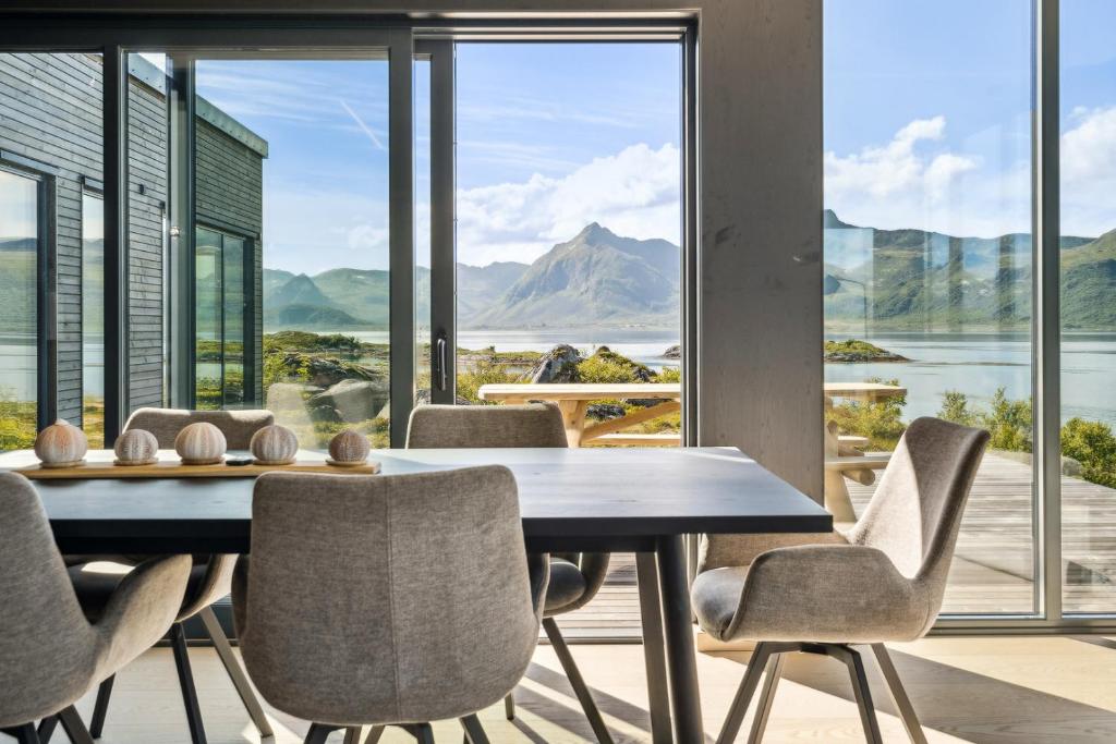 a dining room with a table and chairs and a large window at Lyngvær Arctic Pearl Lodge - Jacuzzi & Sauna - No 17 in Kleppstad