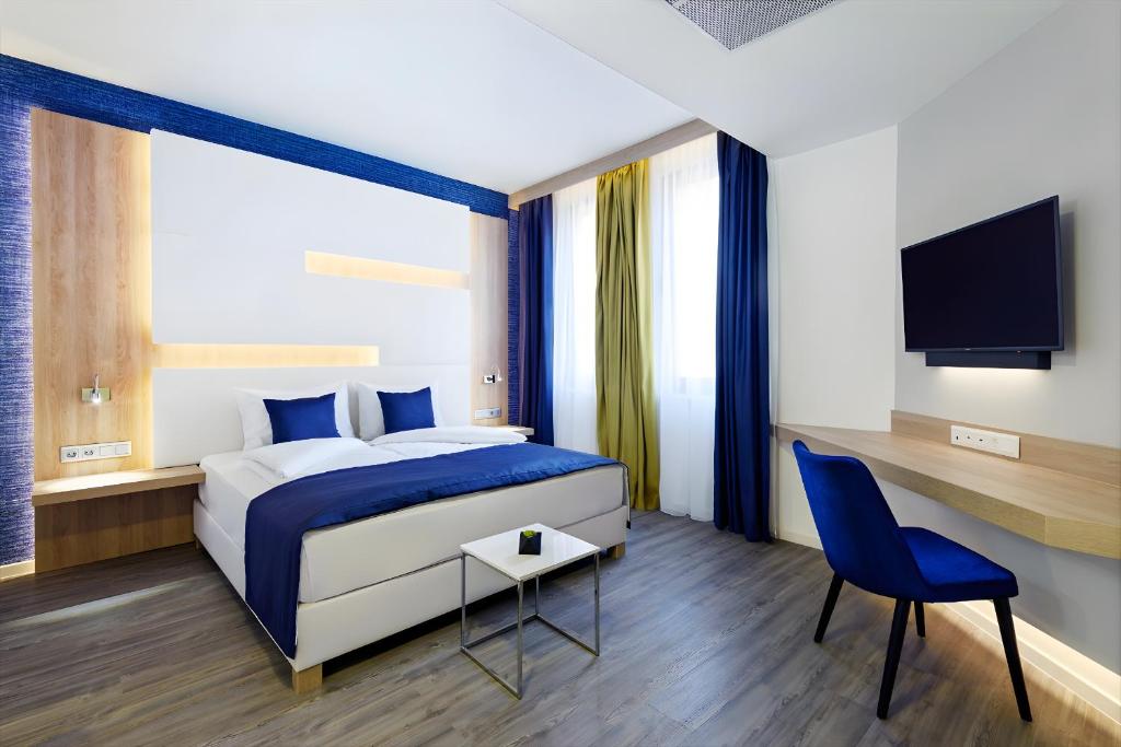 a bedroom with a bed and a desk and a tv at KVi Hotel Budapest - the smart hotel in Budapest