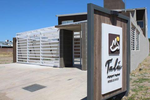 a sign in front of a building with a gate at Talu Apart Hotel in San Rafael