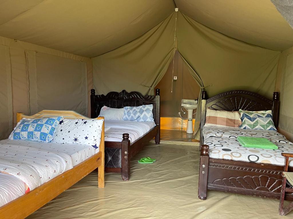 a bedroom with two beds in a tent at Ntito Mara lodge in Maasai Mara National Reserve