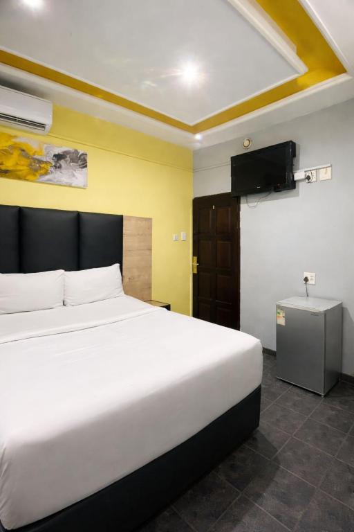 a bedroom with a large white bed and a television at Hotel Metro Lodge Xpress in Durban