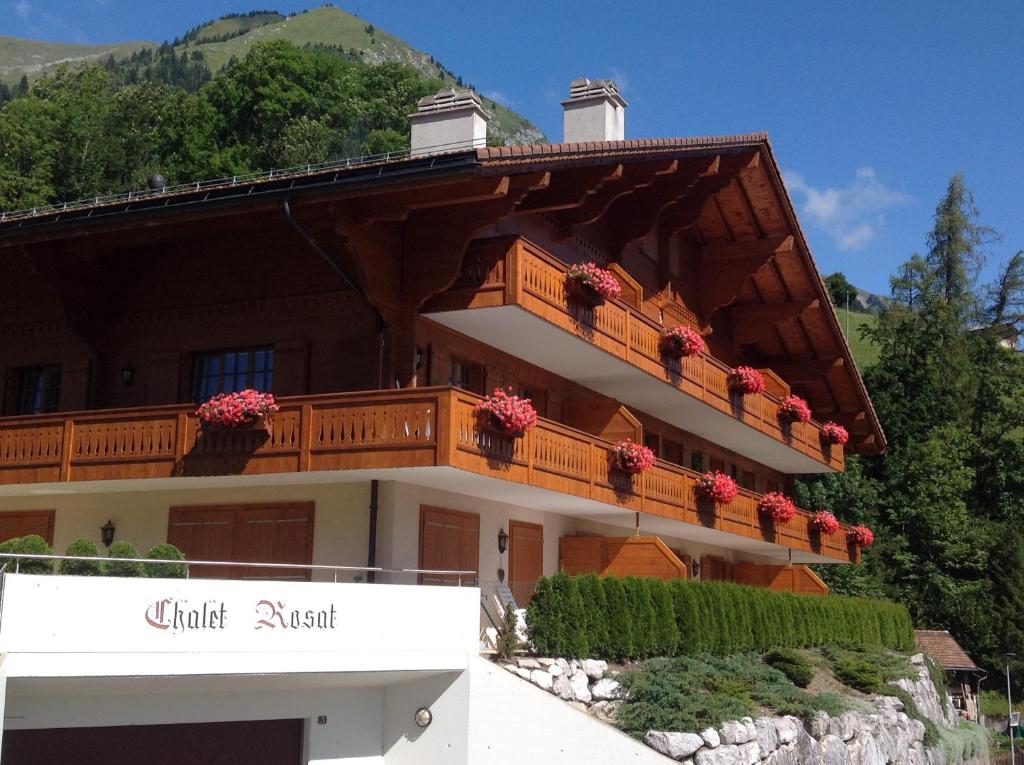 ein Gebäude mit einem Balkon mit Blumen darauf in der Unterkunft Le Chalet Rosat Apartment 25 in Chateau-d'Oex