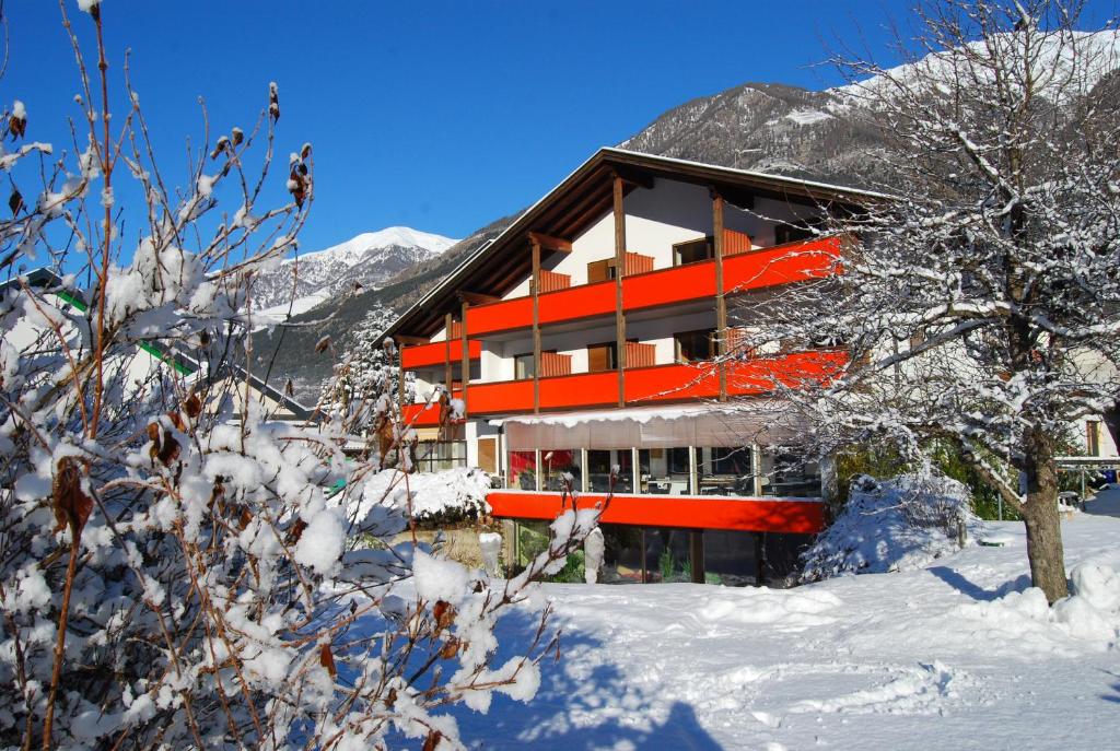 a building in the snow in front of a mountain at Apartments GoldRain in Coldrano
