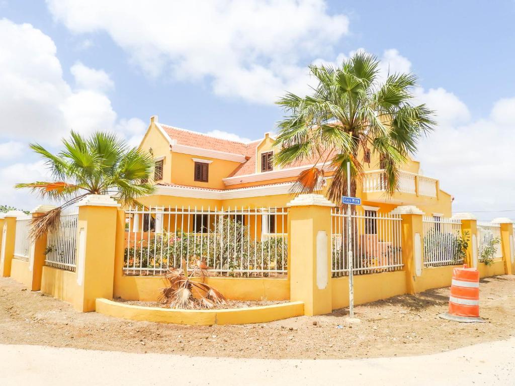 a yellow house with palm trees in front of it at Landhuis Belnem Bonaire in Kralendijk