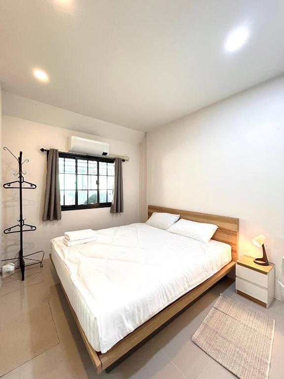 a bedroom with a large white bed with a window at Airport Cozy House - Suvarnabhumi in Samutprakarn