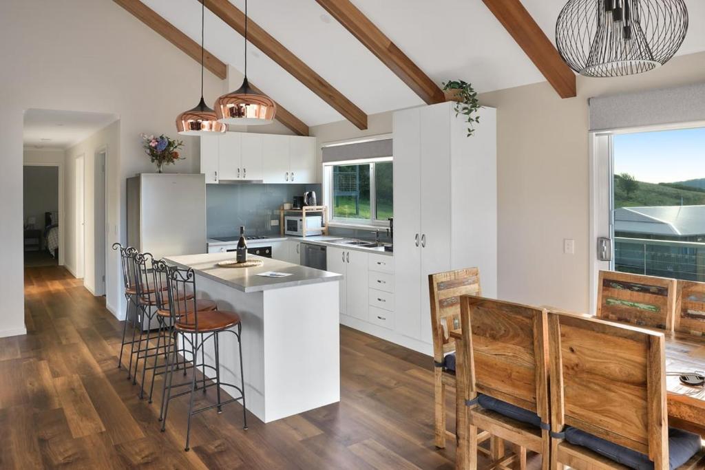 a kitchen with white cabinets and a table and chairs at Spotted Gum -Merrijig in Merrijig
