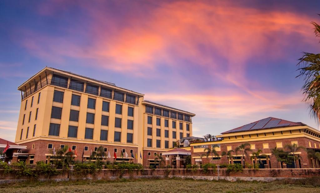 a large white building with a sunset in the background at Soaltee Westend Premier in Nepālganj