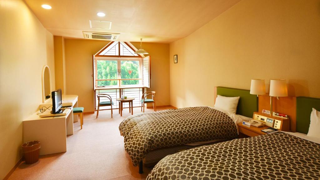 a bedroom with two beds and a table and a window at ホテル秘境の湯 in Miyoshi