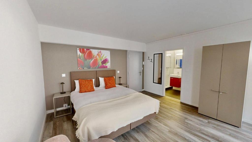 a bedroom with a large white bed with orange pillows at Apartmenthouse Viktoria in Bern in Bern