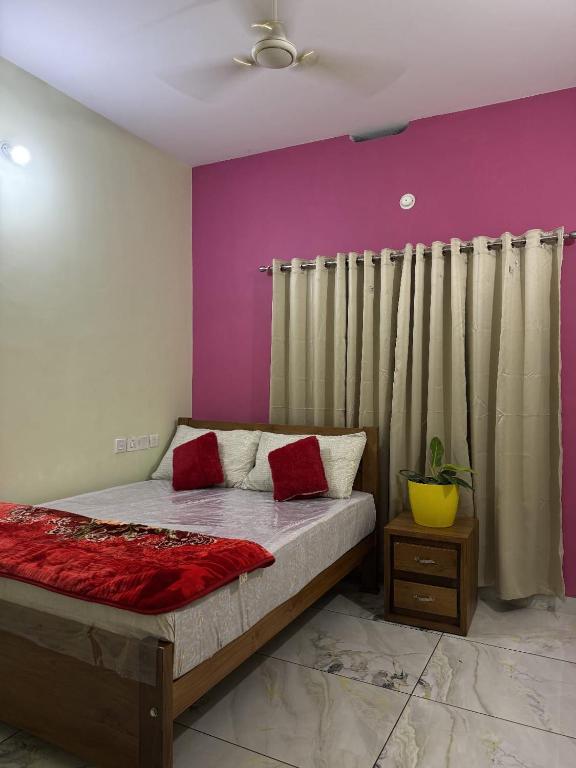 a bedroom with a bed with red pillows on it at Mountain pride homestay in Meppādi