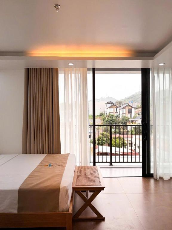 a bedroom with a bed and a view of a balcony at La Mer Cat Ba Boutique Hotel in Cat Ba