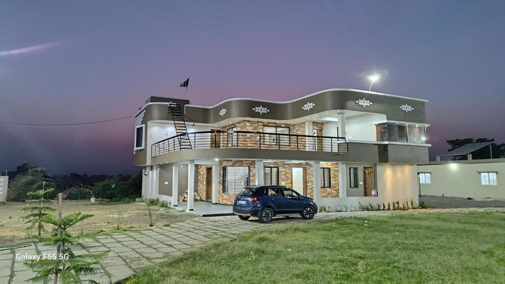 a car parked in front of a large house at Raghav Sarkar Parisar in Indore