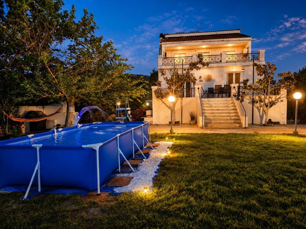 a pool in front of a house at night at Luxury 6BR Villa, Garden Oasis, near Schinia Beach in Káto Soúlion