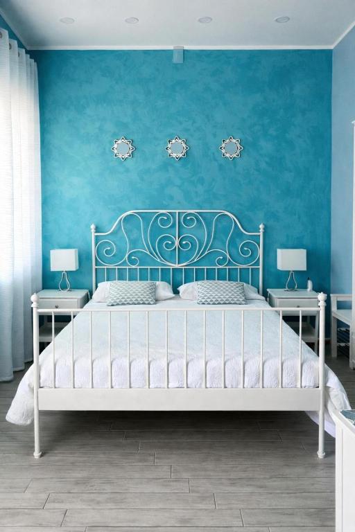 a bedroom with a bed with a blue wall at Ciao Ciao Rooms in Letojanni