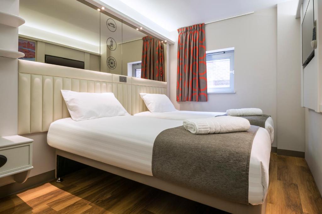 a bedroom with two beds and a window at Point A Hotel London Shoreditch in London