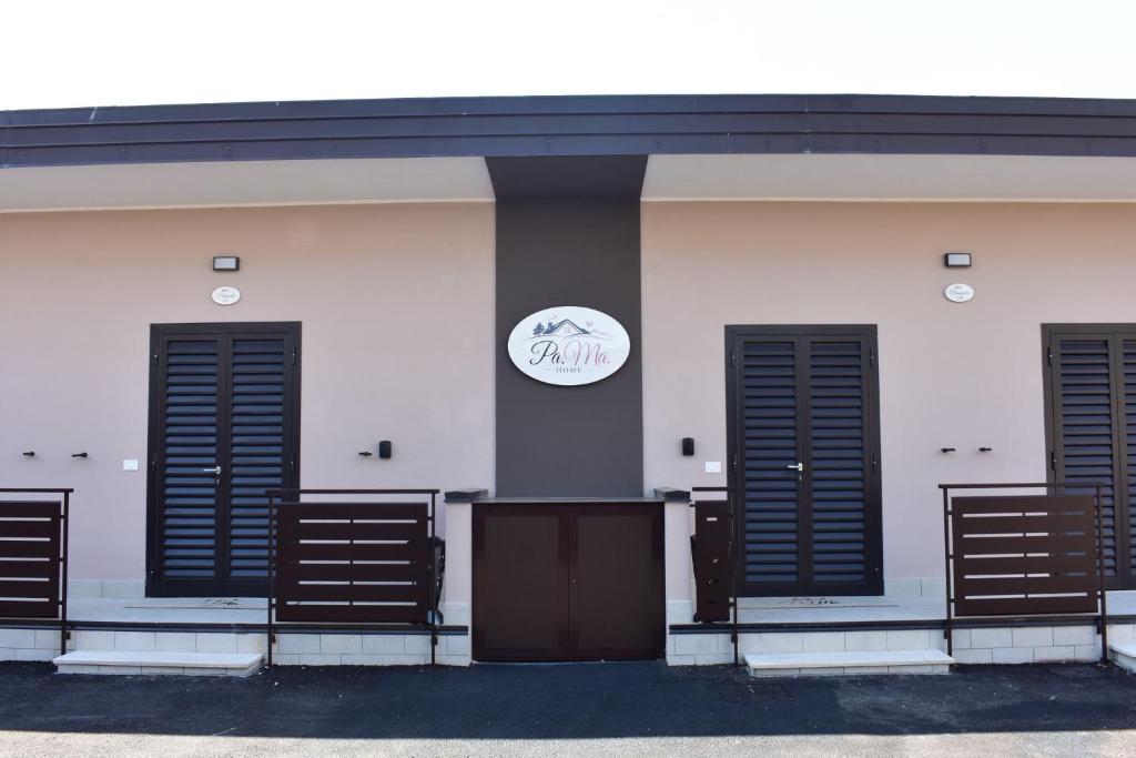 a white building with black doors and a sign on it at PAMA Home in Acerra
