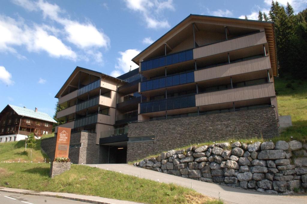 a building with a stone wall in front of it at Aparthotel Alpinresort Damüls in Damuls