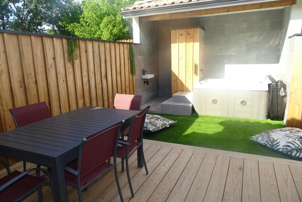 a patio with a table and chairs and a garden at Escapade Bassin - Spa Privé - Maison 6 Pers in Audenge