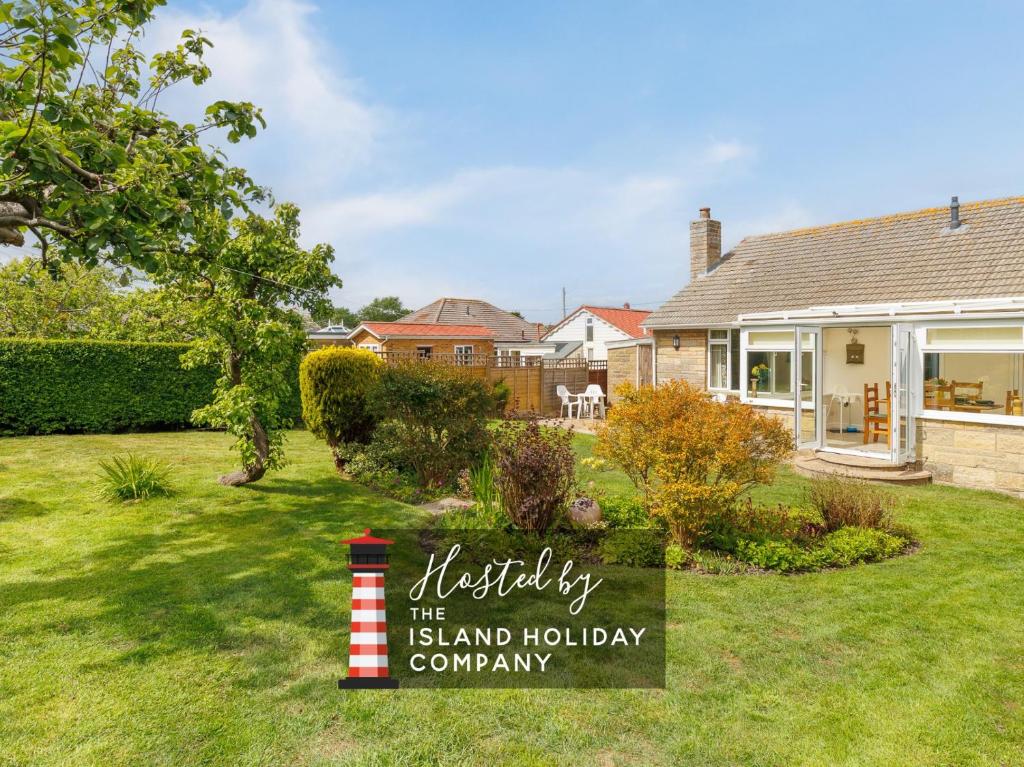 a house with a sign in a yard at Westway - 3 Bed Coastal Bungalow with Large Garden Steps from Colwell Bay Beach in Freshwater