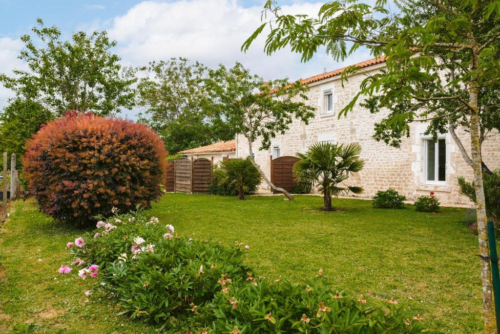 a house with a yard with flowers and trees at Gîte Les Bougrines - Marais in Fontaines