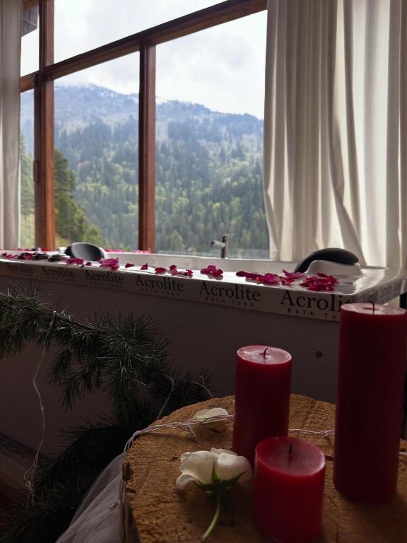 a bath tub in a room with a table with red candles at The Swayambhu Hamta in Manāli