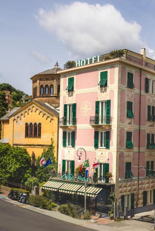 ein rosafarbenes Hotel an einer Straßenseite in der Unterkunft Hotel Stella in Rapallo