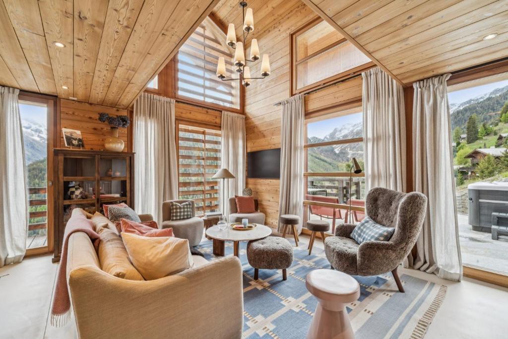 a living room with a couch and chairs and windows at Chalet SkyLodge by Mrs Miggins in Grimentz