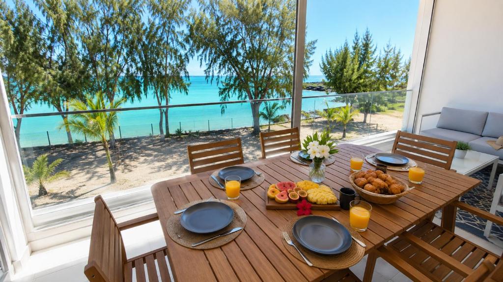 a wooden table with a bowl of fruit and a view of the beach at Seaside Escape with Breathtaking View in Grande Gaube