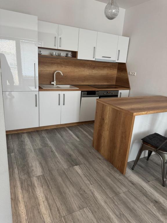 a kitchen with white cabinets and a wooden counter top at Apartman David Topoľčany in Topoľčany