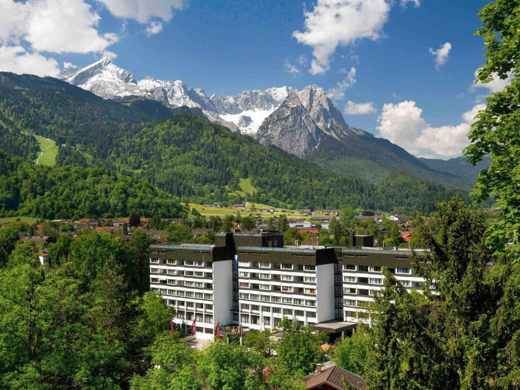 a building in front of a mountain range at Sunday Hotel Garmisch Partenkirchen in Garmisch-Partenkirchen