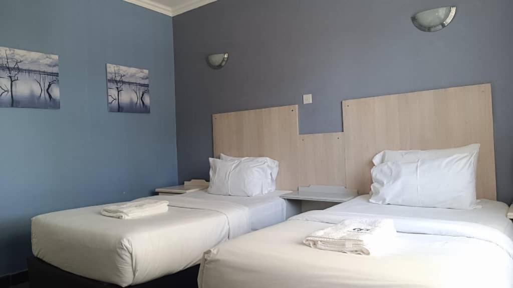 two beds in a room with blue walls at Resta Lodge in Kariba