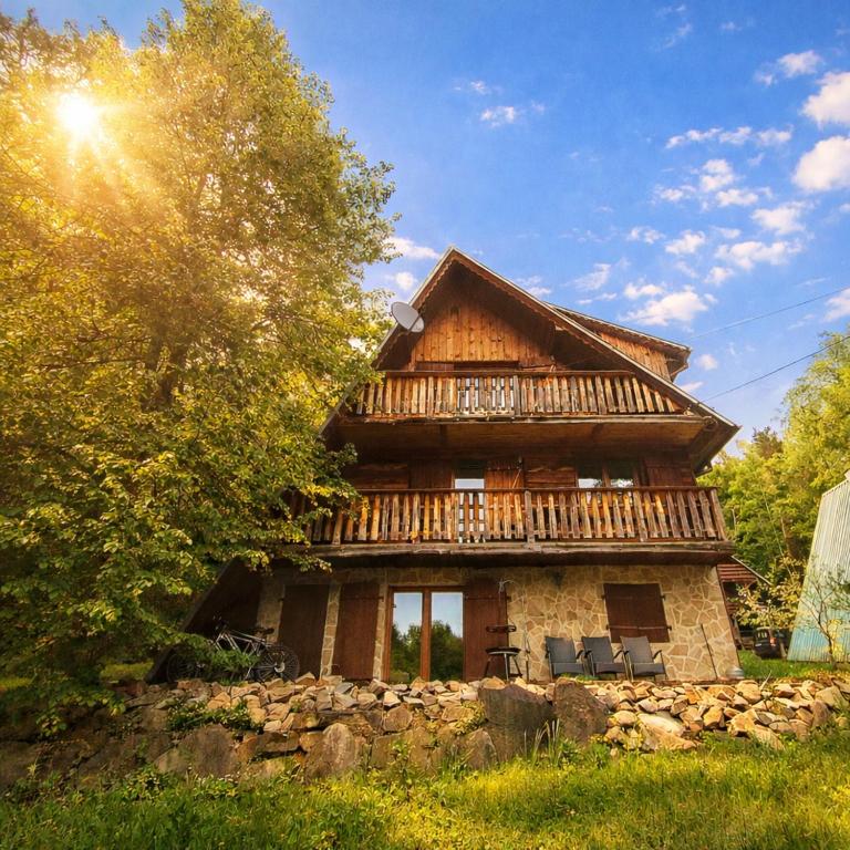 a large wooden house with a stone wall at Leśny Poranek in Iwkowa