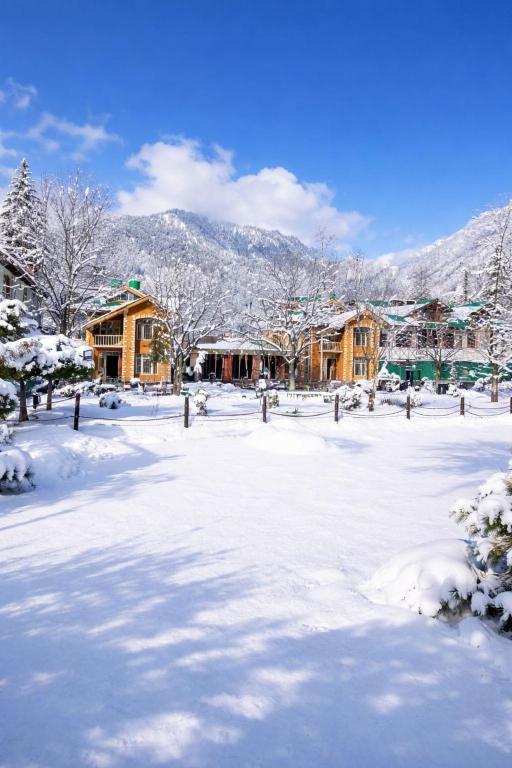 a yard covered in snow with houses and mountains at Lidder view resort in Muski