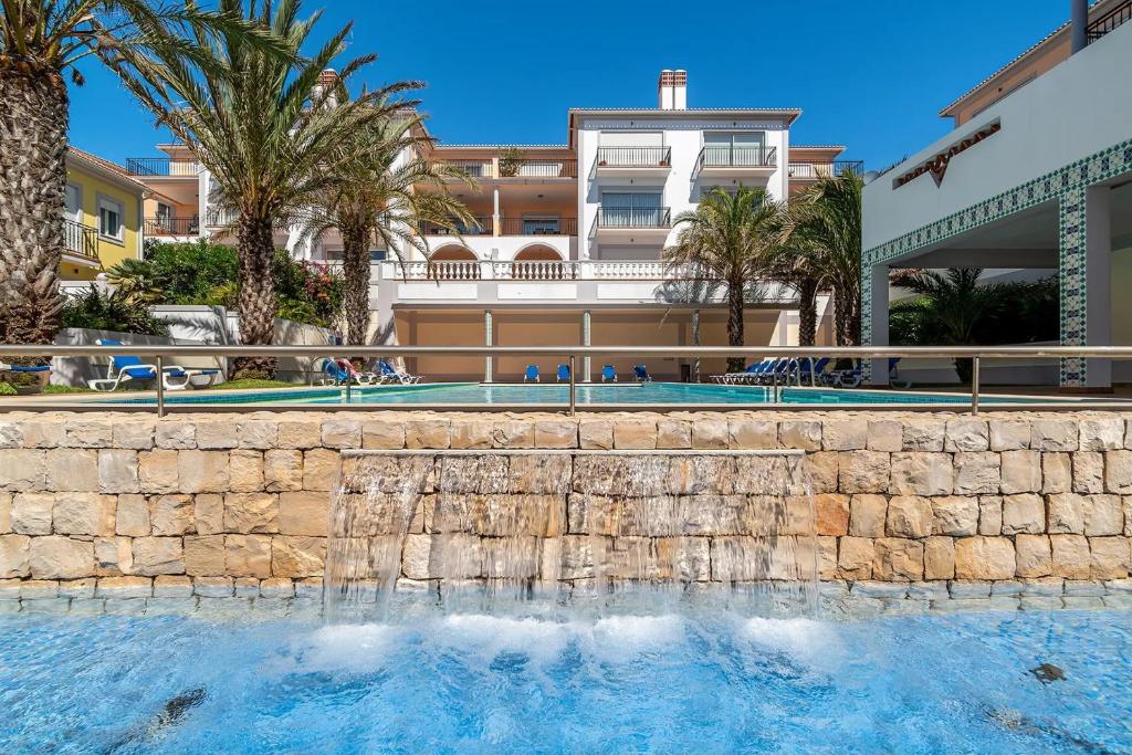 a swimming pool in front of a building with palm trees at SUNSET Apartment in Amoreira