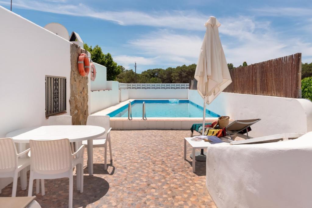 a patio with a table and an umbrella and a pool at Casa Susana in Santa Eularia des Riu