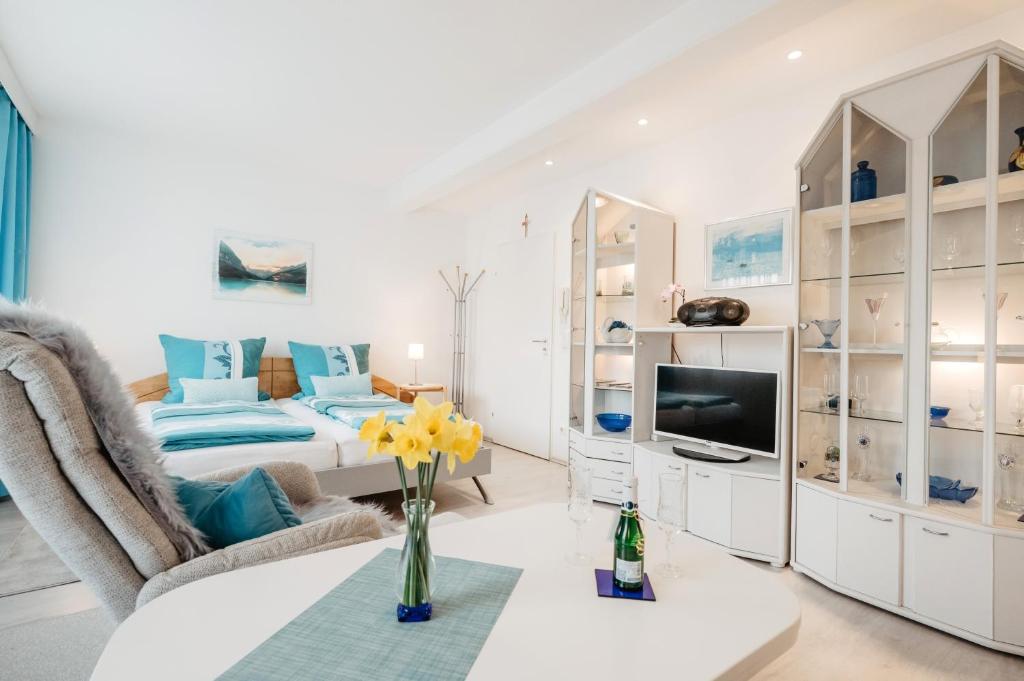 a white living room with a bed and a tv at Ferienappartement Donautal in Obernzell