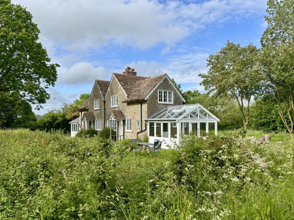an old house with a greenhouse in a field at South Cottage in Sherborne