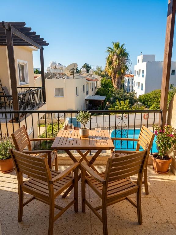 a wooden table and chairs on a balcony with a pool at Sirena Kings in Paphos
