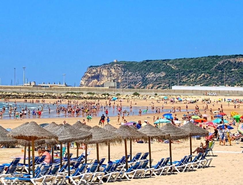 a group of people on a beach with chairs and umbrellas at Villa guiris in Barbate