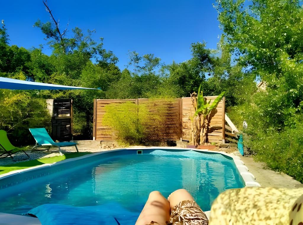 a person laying on a chair next to a swimming pool at La Fée Du Val - Gite En Ardèche in Rosières