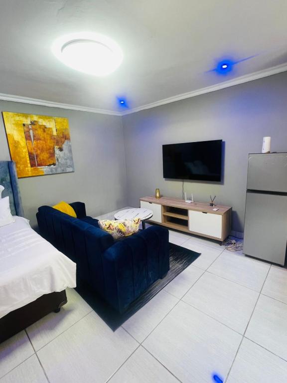 a living room with a blue couch and a flat screen tv at Luxury Executive Apartment in Vanderbijlpark