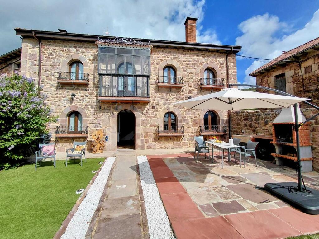 a stone house with a table and an umbrella at Casa Dulcinea en Brañosera Montaña Palentina. in Brañosera