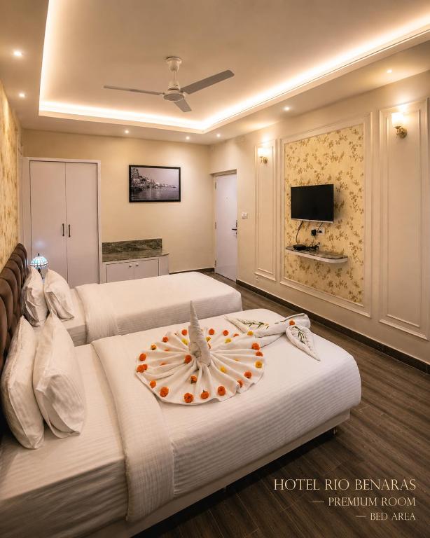 a hotel room with two beds and a flat screen tv at HOTEL RIO BENARAS in Varanasi