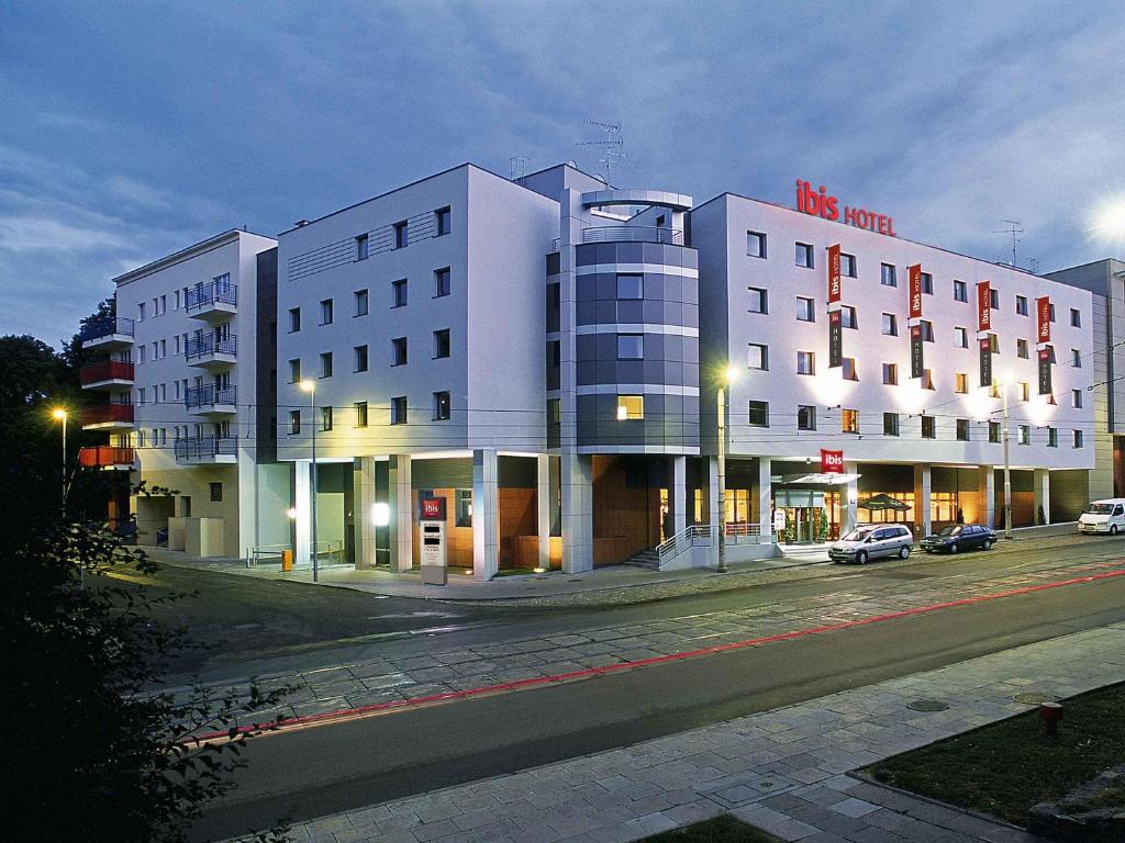 a large white building on a city street at night at Ibis Szczecin Centrum in Szczecin
