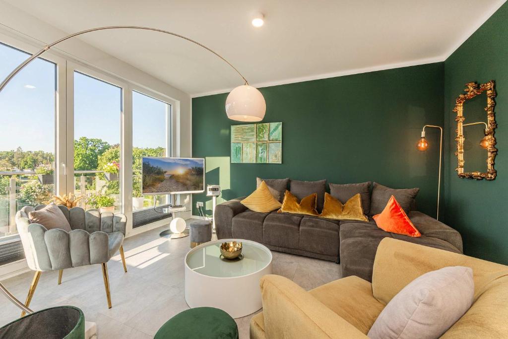 a living room with green walls and a couch and chairs at Ein Traum am Haff in Zirchow